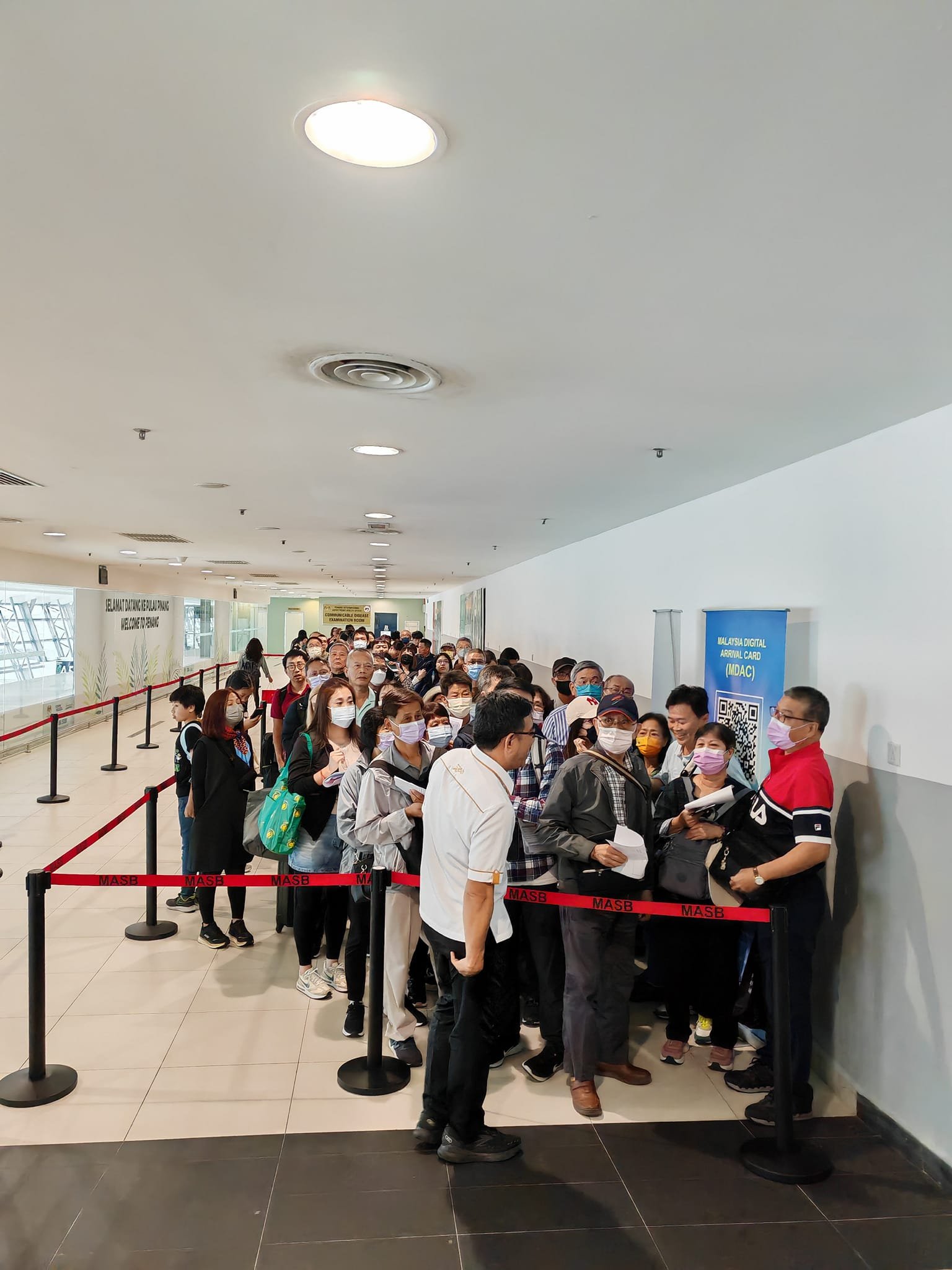 黄汉伟与抵达槟城机场的游客们交流。